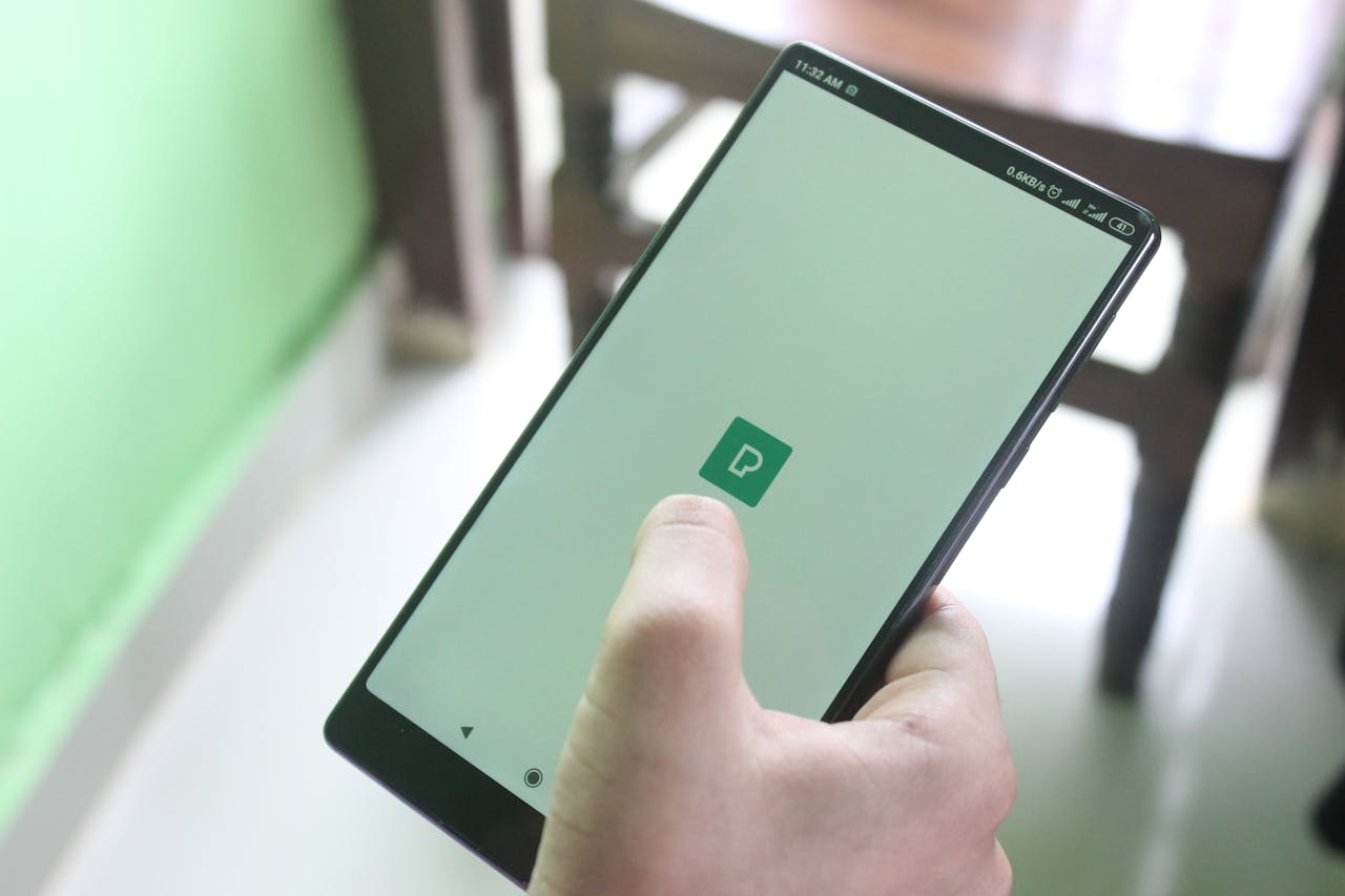 Detailed view of a hand holding a smartphone indoors, showcasing modern technology usage.